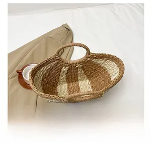 Vue de dessus d'un grand sac cabas tissé marron et beige sur un tissu blanc texturé