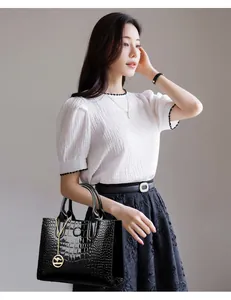 Detail of glossy black faux crocodile leather handbag with golden kangaroo pendant charm