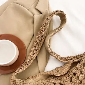 Détail de la large bandoulière tissée d'un sac à bandoulière en paille marron clair d'été