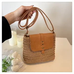 Close-up of handwoven straw crossbody bag with brown leather flap and bronze buttons