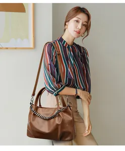 Detail of dark brown tote bag featuring decorative silver metal chain and leather texture