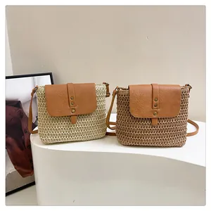 Detailed close-up of woven straw saddle bags in beige and brown with golden rivets