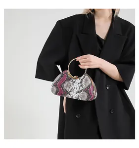 Detailed view of the vibrant snakeskin pattern and golden circular handle on a luxury clutch