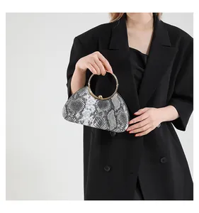 Close-up of snakeskin pattern evening bag with a large golden ring handle worn by a model