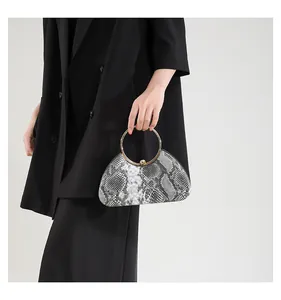 Detailed close-up of snake print evening bag with golden ring handle and metal clasp