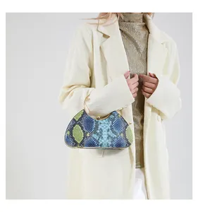 Detail of snake skin texture clutch bag with gold round handle worn by a model