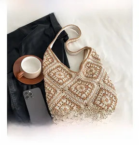 Detail of handmade crochet hobo bag featuring khaki and cream granny square knit pattern