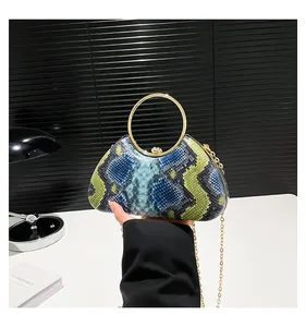 Detail of blue and green snakeskin clutch with gold circular handle and metal chain strap