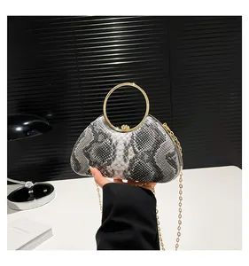 Close-up of snake skin texture and golden metal ring handle on stylish handbag