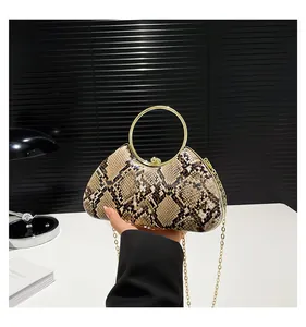 Detail of snake print clutch with gold metal ring handle and fine chain strap