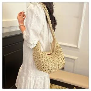 Vue détaillée d'un sac bandoulière en paille tissé à la main sur un mannequin en robe de dentelle