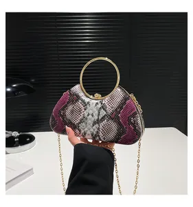 Detail of snake skin texture evening bag with round gold handle and metal chain strap