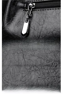 Detail view of silver metal zipper pull and textured lychee grain leather on black tote bag