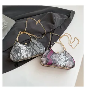 Detailed view of snake skin evening bags with gold ring handles and chain straps