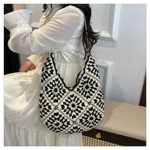 Detailed close-up of a handmade crochet shoulder bag with black and white floral patterns