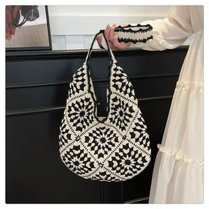 Close-up of black and white crochet tote bag with hollow flower texture and wide strap