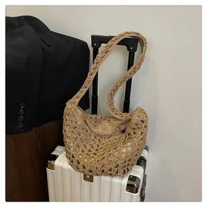 Détail d'un sac à bandoulière en paille tressée sur une valise blanche en voyage