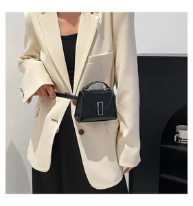 Detailansicht der Mini-Gürteltasche aus schwarzem Leder mit Silberschnalle auf beigem Blazer