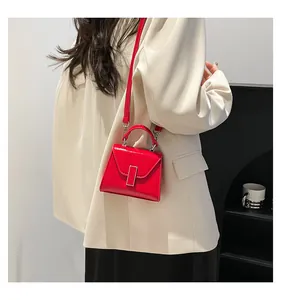 Modell mit einer leuchtend roten Mini-Umhängetasche aus glänzendem Lackleder mit Schloss