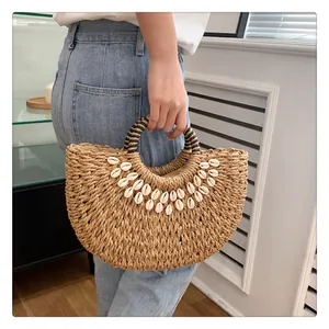 Detail der halbrunden Strohhandtasche mit weißen Muscheln und gestreiften Rundgriffen