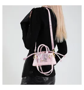 Details einer pinken Eimertasche mit Schlangenmuster, Goldbeschlägen und Kordelzug