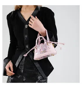 Detailaufnahme der rosa Schlangendruck-Beuteltasche mit goldener Hardware und Füßen