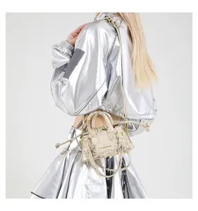 Detail der gold-metallischen Beuteltasche mit Schlangenmuster, Griff und Kordelzug