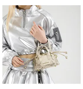 Detailansicht der cremefarbenen Mini-Beuteltasche mit Schlangenmuster und Metallringen