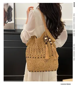 Detail of straw shoulder bag featuring hollow crochet pattern and beaded tassel fringe