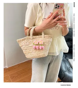 Detailed view of handmade straw handbag featuring crochet pink tulip charms and floral accents