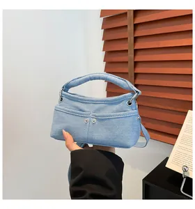 Detail of light blue denim handbag featuring front pockets and metal rivet accents