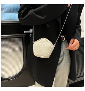 Detail of a creamy white star-quilted pentagon crossbody bag with a slim metal chain strap