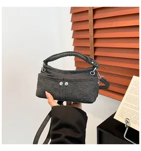 Close-up of dark grey denim fabric texture and silver button details on mini handbag