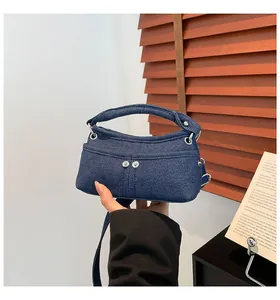 Detail shot of mini navy blue denim crossbody bag with silver buttons and wide handle