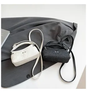 Top-down view of mini canvas square bags in off-white and dark gray with rivet details