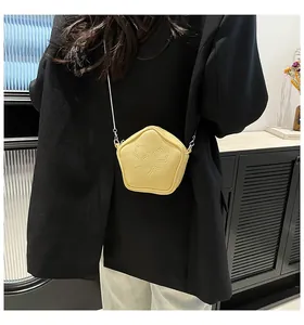 Star-patterned light yellow pentagon bag worn by model with silver chain strap