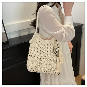 Detailed close-up of beige crochet shoulder bag with tassel and intricate mandala pattern