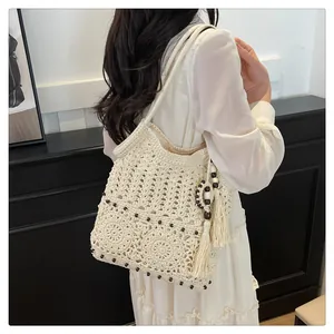 Detail of bohemian cream crochet shoulder bag with hollow weaving and fringe tassels