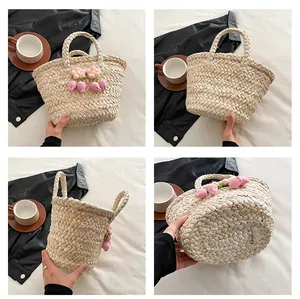 Detail view of woven straw bucket bag with pink flower embroidery and sturdy top handles