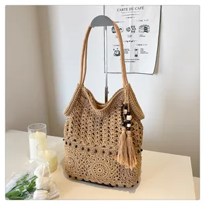 Detailed close-up of straw shoulder bag featuring fringe and hollow woven patterns