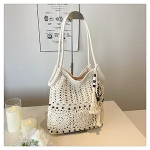 Close-up of handmade cream crochet tote bag with tassels and wooden beads detail