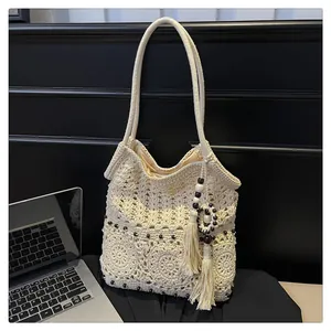 Detail of hollow woven shoulder bag featuring fringe tassel and wooden bead accents