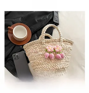 Detail shot of straw woven bag featuring pink crochet flower and round handle