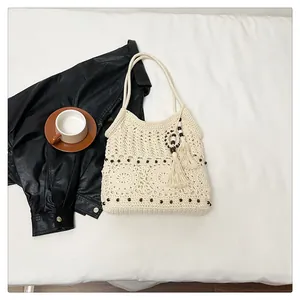 Close-up of bohemian crochet shoulder bag with floral cutouts and wooden beads