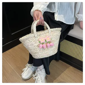 Detail of hand-woven straw bag featuring delicate pink crochet flowers and top handles