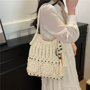 Chic cream hollow woven straw bag with beads and tassels for beach vacations