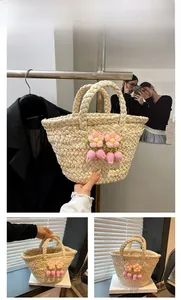 Detail of hand-woven straw bag featuring decorative pink crochet flowers and top handles
