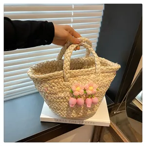 Detail of handmade straw handbag with crochet pink flowers and woven handles