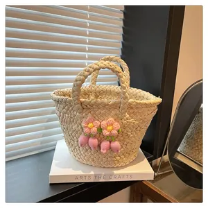 Detail of white straw handbag with pink crochet flowers on decorative books in sunlight