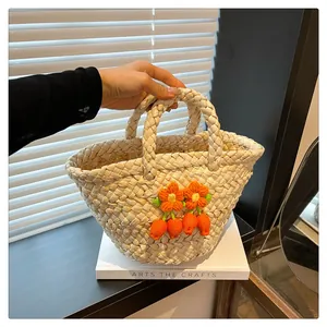 Close-up of handmade straw basket bag with vibrant orange crochet flowers on front